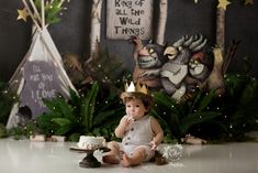 a baby sitting on the floor in front of a cake with a crown on it