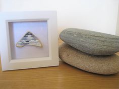 two rocks sitting next to each other in front of a white frame with a rock shaped like a triangle