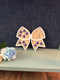 two wooden bow magnets sitting on top of a blue table next to a flower