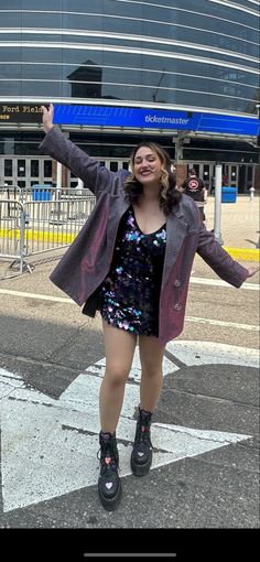 a woman is standing in the street with her arms up and legs spread out,