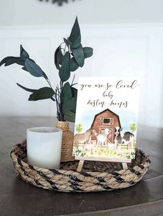 a basket with a card on it and a candle sitting in front of it next to a potted plant