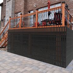 an iron fence with chairs on it in front of a brick building and stairs leading up to the second floor