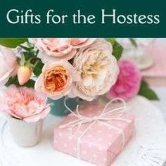 pink flowers are in a vase on a table with a gift wrapped in a ribbon