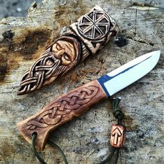 an intricately carved knife is sitting on a piece of wood