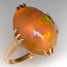 an orange fire opal is set in a yellow gold ring