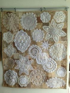 an old wall hanging with crocheted doily on it and some flowers in the middle