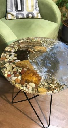 a coffee table with rocks and gravel on it sitting in front of a green chair