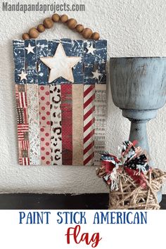 an american flag wall hanging on the wall next to a vase with a wooden bead decoration