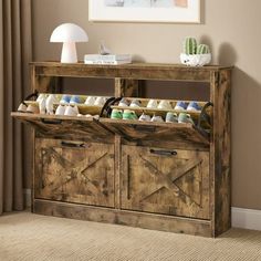 a wooden cabinet with two doors and baskets filled with baby shoes on top of it