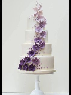 a three tiered white cake with purple flowers on top