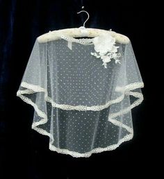 a wedding veil hanging from a hanger on a black background with white polka dots