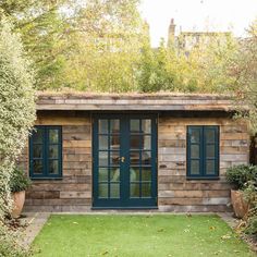 a small wooden building sitting in the middle of a lush green yard