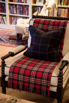 a chair with a plaid blanket on it in front of a bookshelf