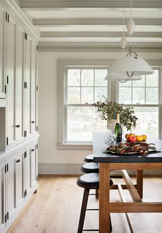 a kitchen with white cabinets and black counter tops next to a wooden dining room table