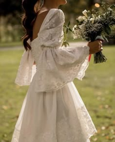 a woman in a white dress holding a bouquet of flowers and looking off into the distance