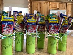 several green mason jars filled with candy and snacks