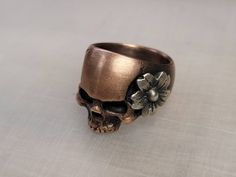 shibuichi (10% silver, 90% copper) with a sterling silver cherry blossom  Size 7.75 18mm tall, 15mm wide across the face 8mm wide band Handmade Adjustable Vintage Skull Ring, Adjustable Vintage Skull Ring Gift, Unique Skull Rings For Gifts, Unique Nickel-free Skull Ring, Symbolic Handmade Skull Ring Gift, Handmade Symbolic Skull Ring As Gift, Unique Nickel-free Skull Ring Gift, Handmade Symbolic Skull Ring For Gift, Handmade Bohemian Skull Ring For Gift