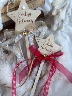 two wooden stars on top of each other with red ribbons and bows in front of white fur