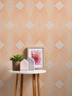 a white table with a potted plant on top of it next to a wallpaper