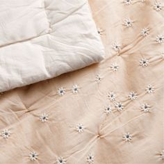 an unmade bed with white sheets and flowers on it's coverlet next to a pillow