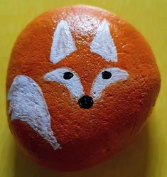 an orange painted like a fox with black eyes