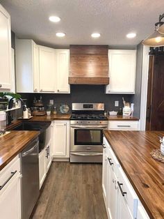 a kitchen with white cabinets and wood counter tops, stainless steel appliances and dishwasher