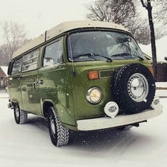 an old green van is parked in the snow