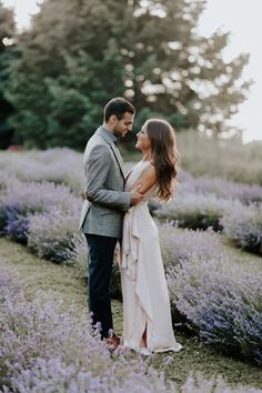 a man and woman standing next to each other in a lavender field