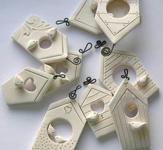 six white birdhouses with holes and string attached to the top, all in different shapes and sizes