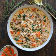 a bowl of soup with carrots and spinach in it on a wooden table