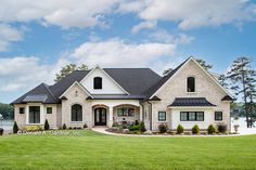 a large white house sitting on top of a lush green field next to a lake