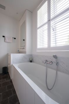 a large white bath tub sitting next to a window