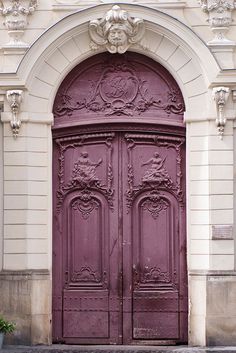 an ornately decorated purple door in front of a white building with arched doorways