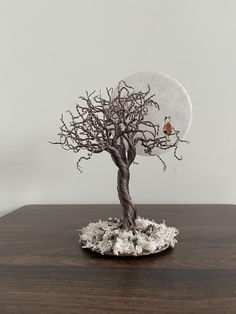 a small tree on a wooden table with a bird perched on it's branch