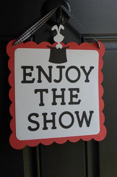 a sign that says enjoy the show hanging from a door handle on a black door