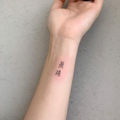 a woman's arm with a small wrist tattoo that has chinese characters on it