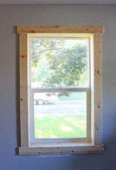 a window in the corner of a room that is painted blue and has wood trim around it