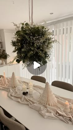 a dining room table is decorated with candles and greenery for the centerpieces