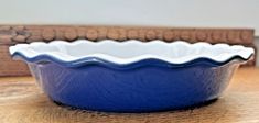 a blue pie dish sitting on top of a wooden table next to a cutting board