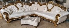 a white couch with gold trimmings and a foot stool