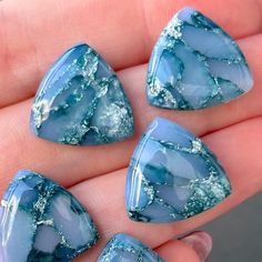 three pieces of blue glass sitting on top of a person's hand