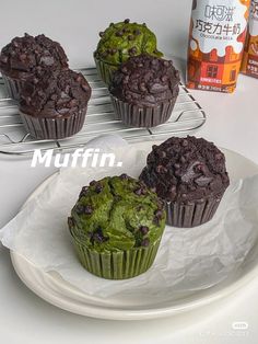 three chocolate muffins sitting on top of a white plate next to a bottle of orange juice