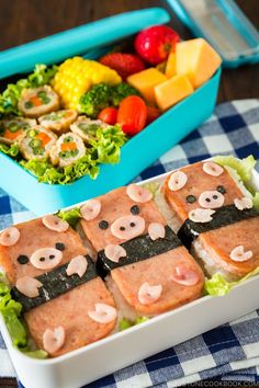 two trays filled with food on top of a blue and white table cloth next to each other