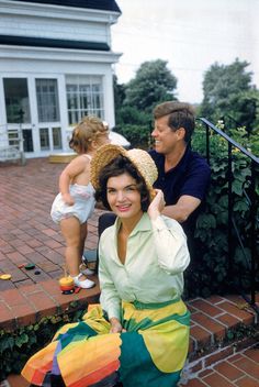 a woman sitting on top of a wooden bench next to a man in a hat