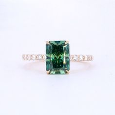 an emerald colored diamond ring with diamonds around it