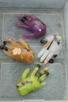 four plastic hand puppets sitting on top of a glass table next to eachother