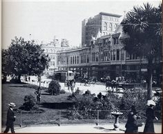 an old black and white photo of people walking on the street in front of buildings