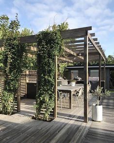 an outdoor dining area with wooden decking and pergolated trellis on the roof