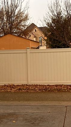 a fire hydrant sitting on the side of a road next to a white fence