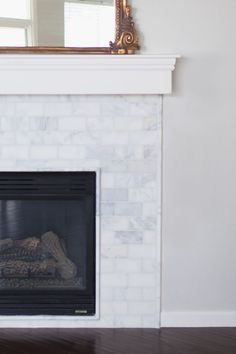 a white fireplace with a mirror above it